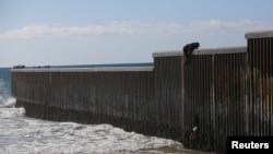 ایک امیگرینٹ سرحدی باڑ پر چڑھ کر امریکہ میں داخل ھونے کی کوشش کر رہا ہے۔ فوٹو رائٹرز